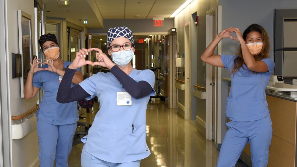 enfermera con máscara facial haciendo un corazón con las manos