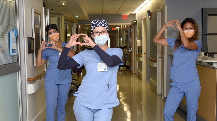 nurse practitioner wearing a face mask and making a heart shape with her hands