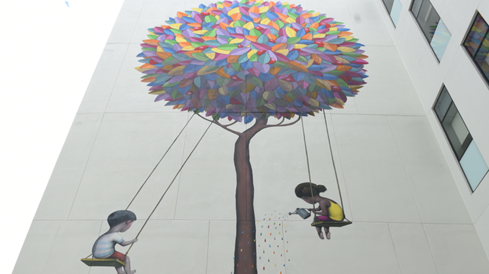 mural de árbol colorido y niños en columpios