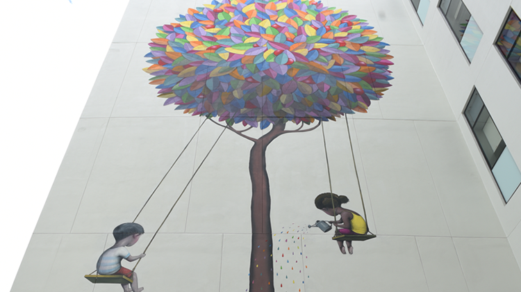 mural de árbol colorido y niños en columpios