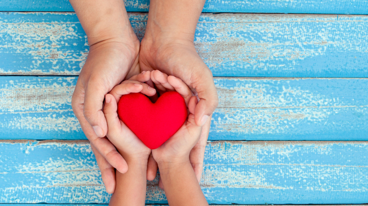 A parent and child hands holding hearts  