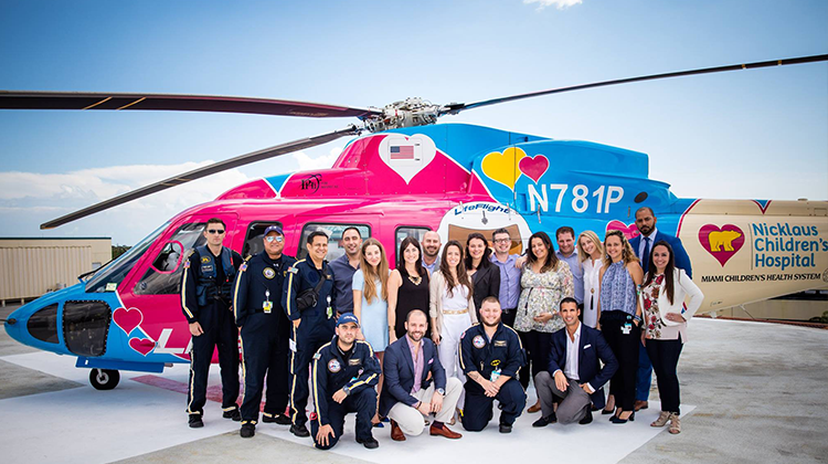miembros NCYA y del equipo de emergencias posando en frente del helicóptero