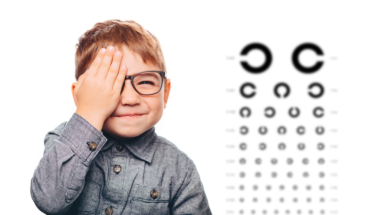child covering eye during eye exam.